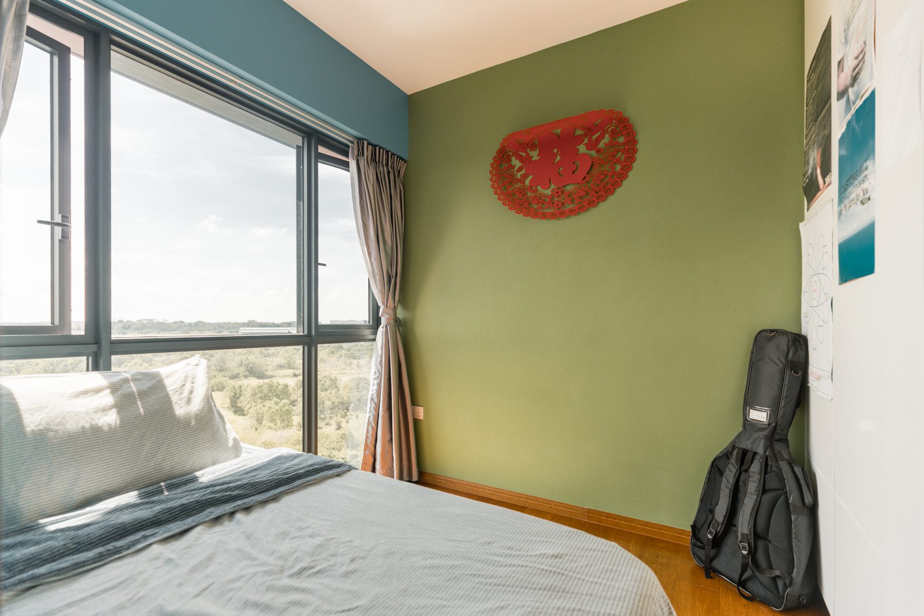 Bedroom 3 with sage-green accent wall and a large window framing the forest view