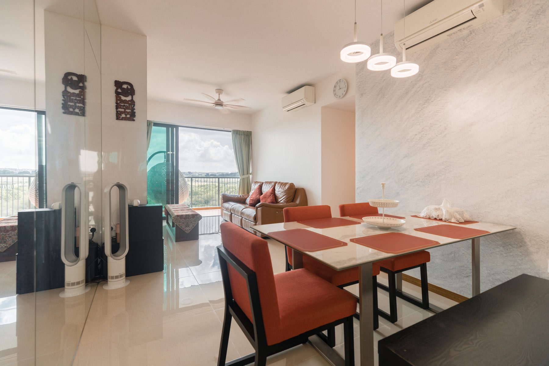 Dining area with marble-top table, red upholstered chairs, and view through to the living room and balcony