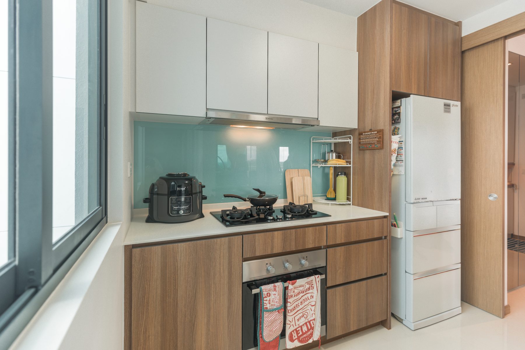 Kitchen cooking area with gas hob, oven, and refrigerator