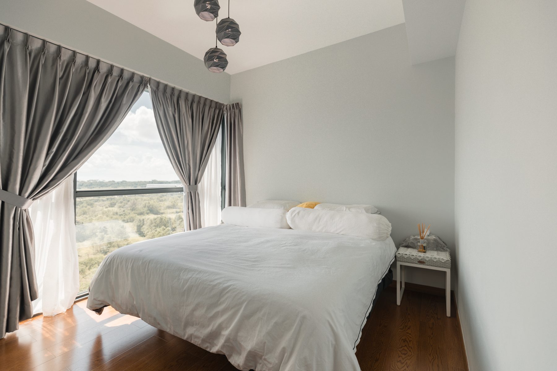 Master bedroom with king bed, silver curtains, pendant lamps, and forest-view picture window