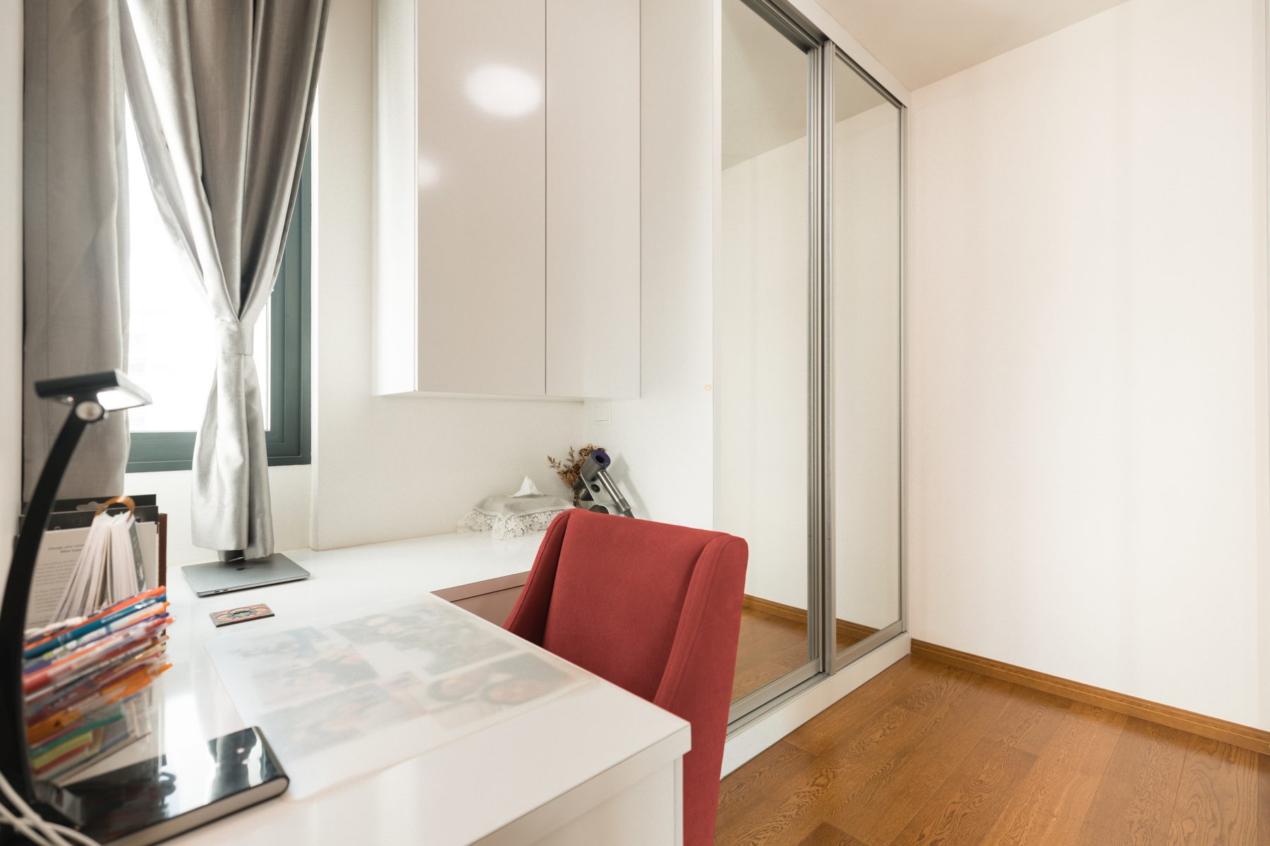 Walk-in wardrobe with mirrored sliding doors and a vanity desk by the window